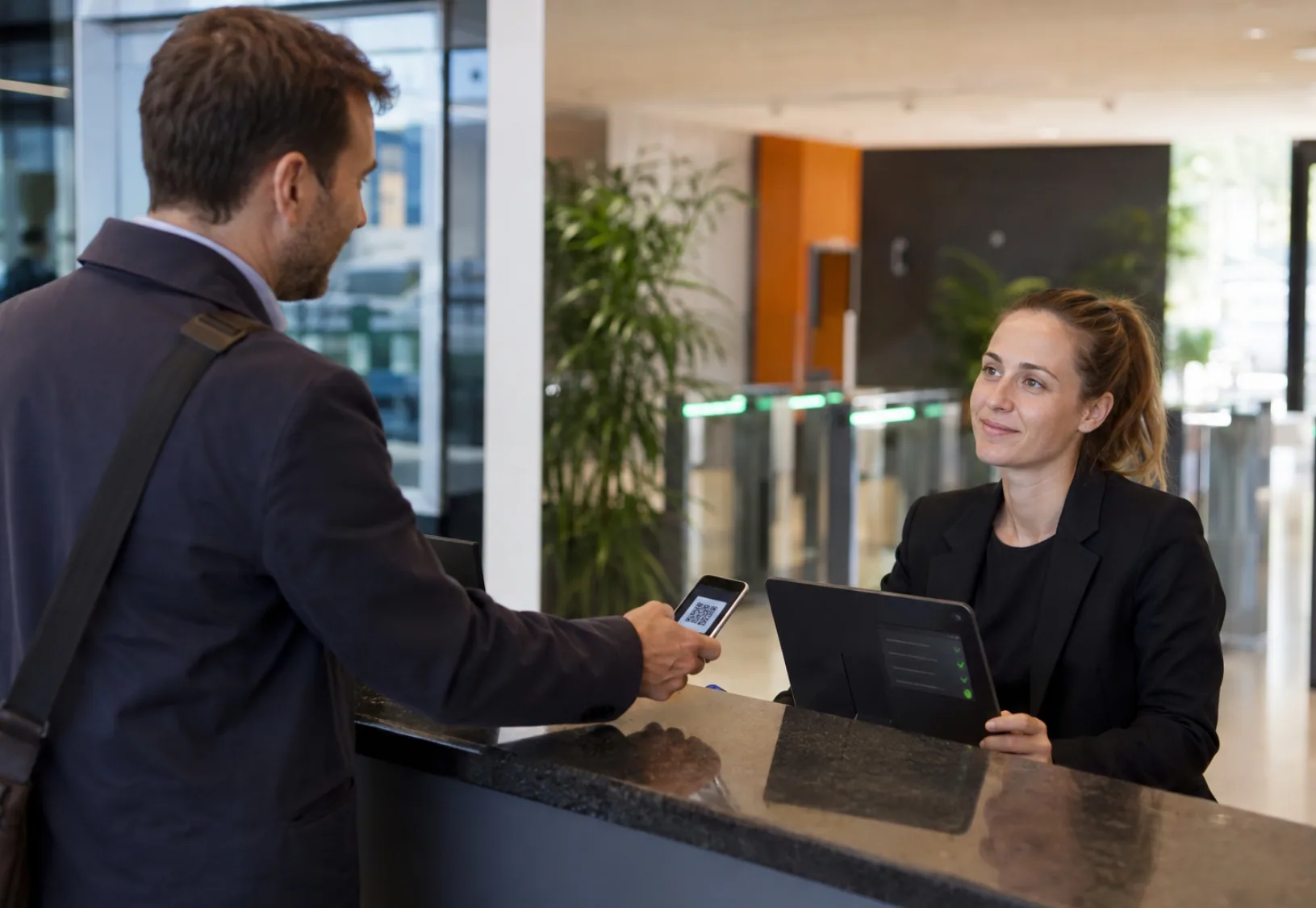Receptionist checking a visitor's identification using their QR code