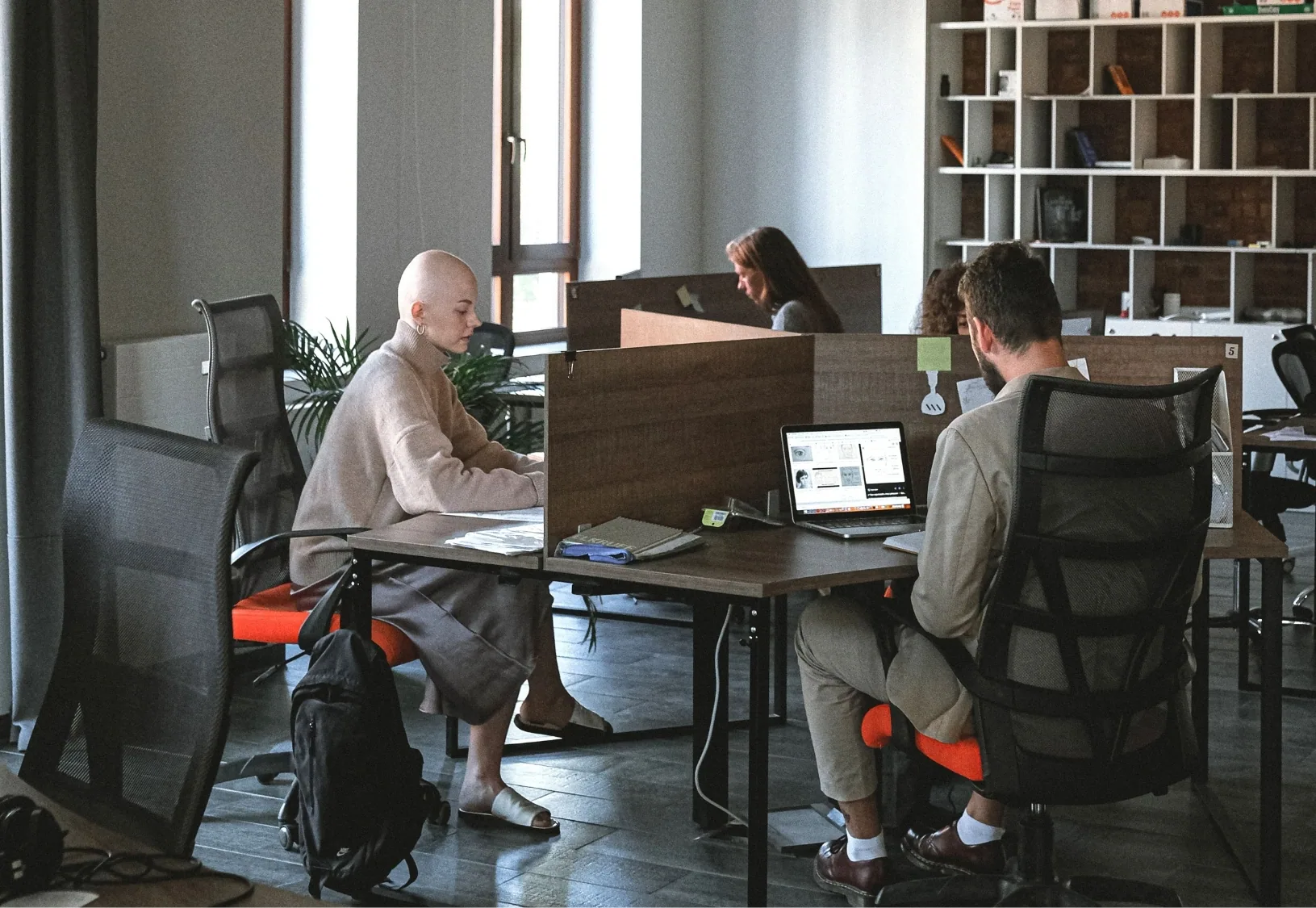 Employees seated at workstations in an open-plan office organised with shared desks.