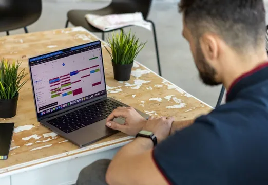 Employee checking a calendar on a laptop to organise desk and car park bookings.