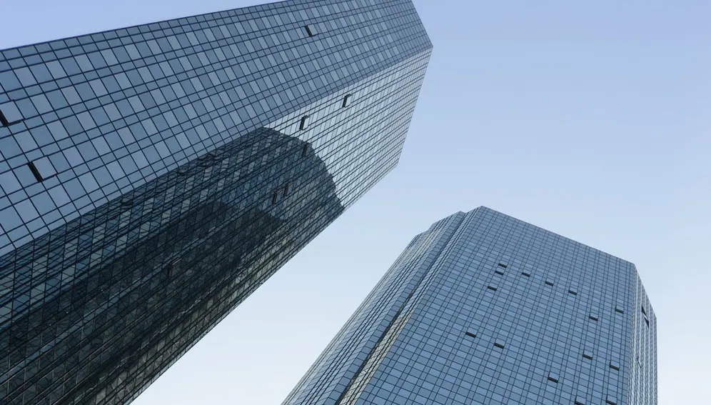 Low-angle view of two modern office buildings with glass façades, illustrating professional work environments.