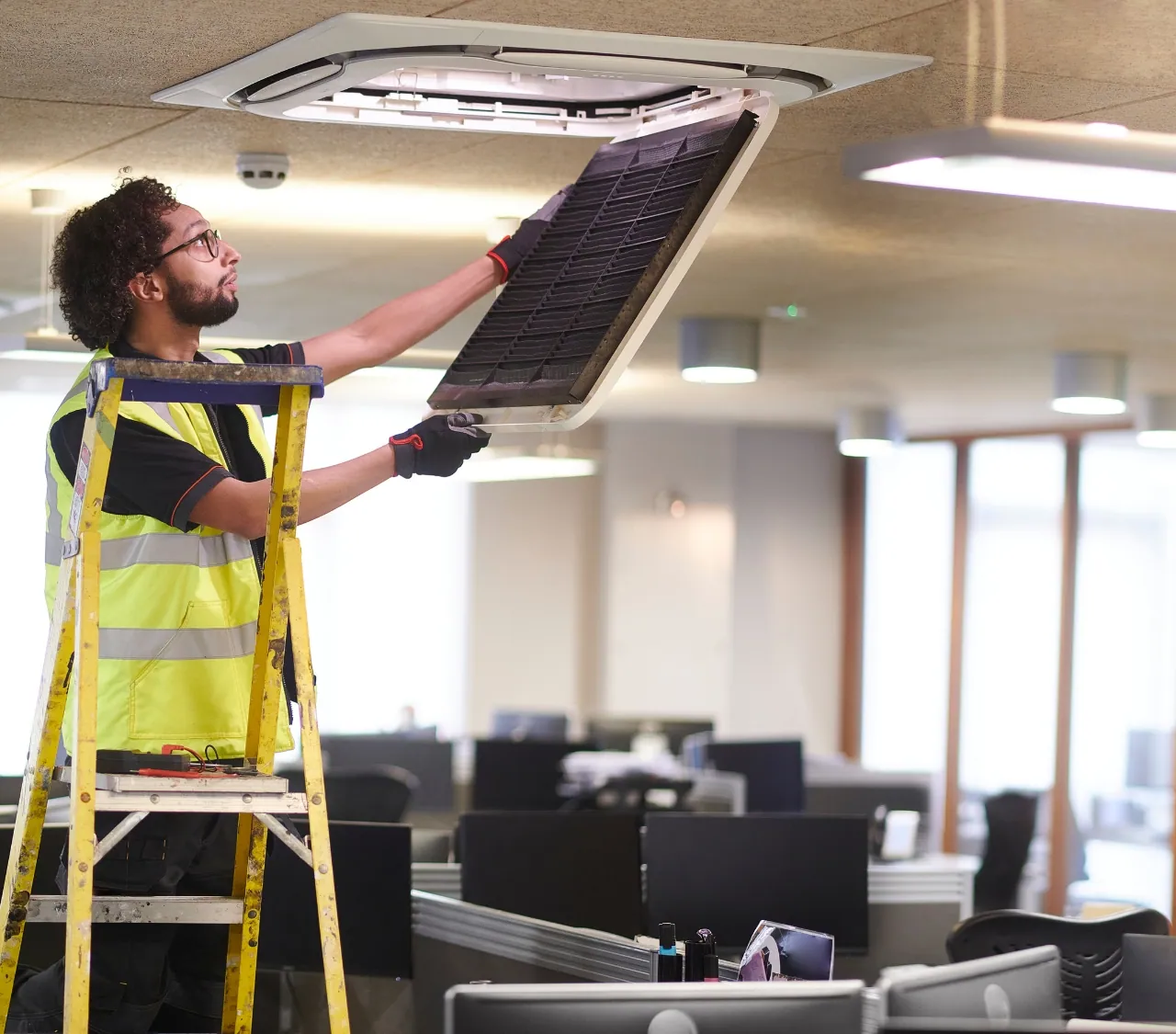 Technicien réalisant une intervention de maintenance sur un système de climatisation dans des bureaux