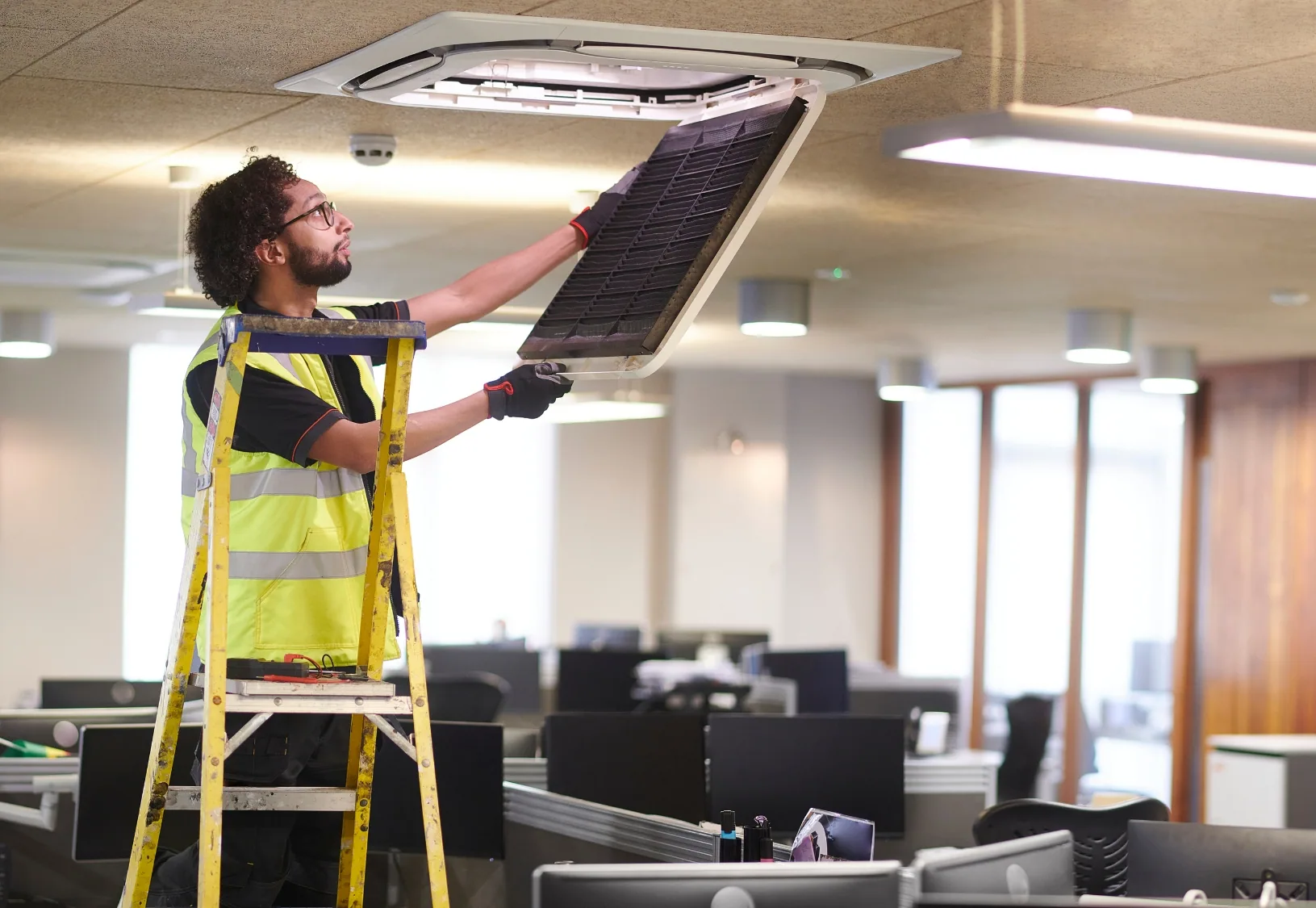 Technician servicing an air conditioning system in an office