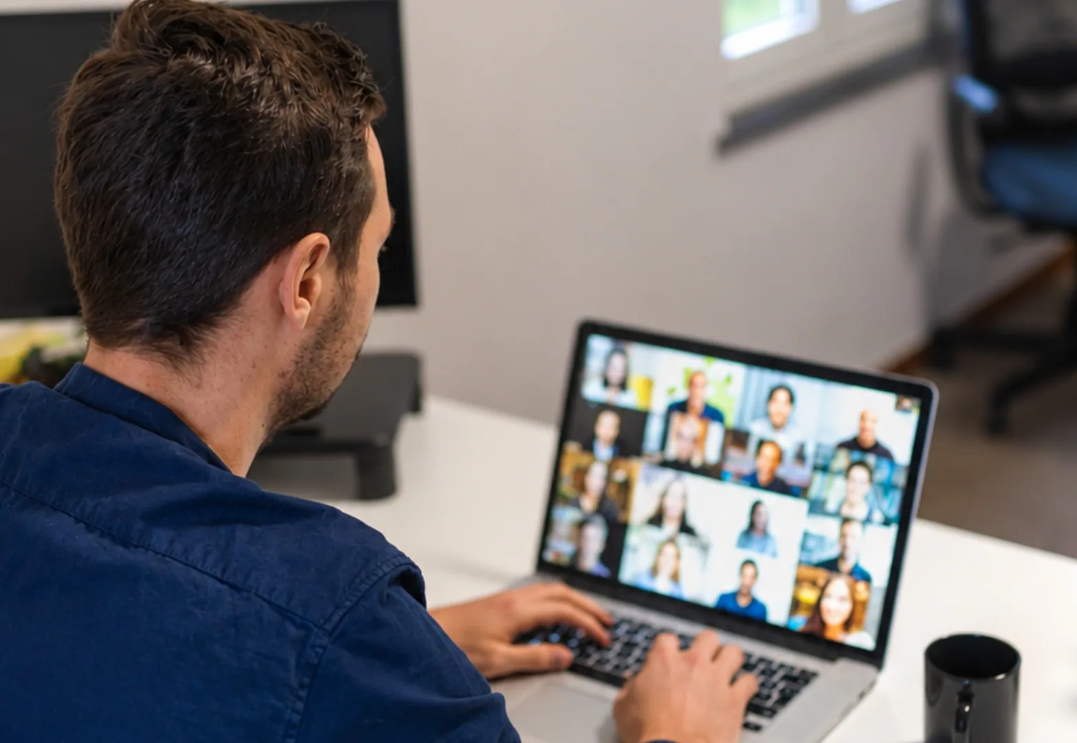 Employee on a video call with several colleagues from a laptop, illustrating a hybrid meeting.