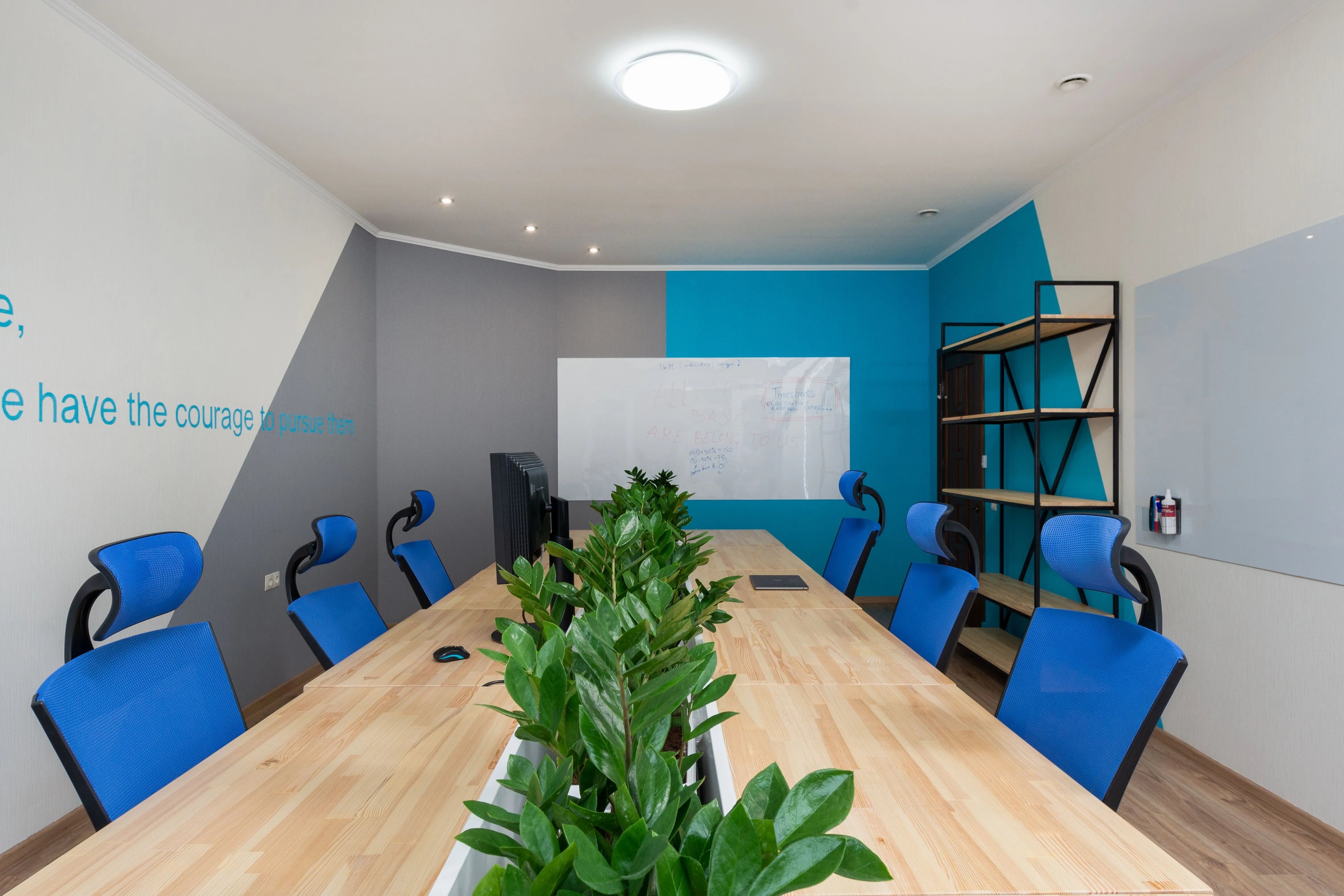Salle de réunion vide avec une grande table et des chaises bleues, illustrant le problème des salles fantômes en entreprise.