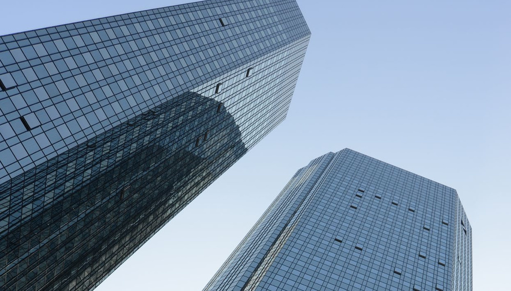 Low-angle view of two modern office buildings with glass façades, illustrating professional work environments.