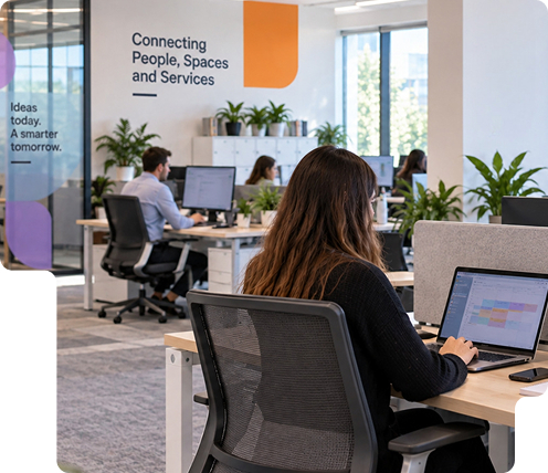 Employees working in a modern open-plan office with shared desks and collaborative spaces